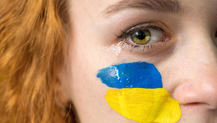 Una donna in lacrime con la bandiera ucraina dipinta sulla guancia, rappresentando il dolore e la speranza del popolo ucraino